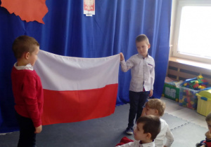 Dwaj chłopcy trzymające flagę Polski.